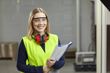 Porträt einer lächelnden Arbeitnehmerin in Arbeitsschutzkleidung - ZEDF03242