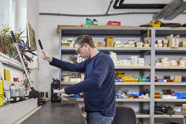 Man using punching machine in workshop - ZEDF03244