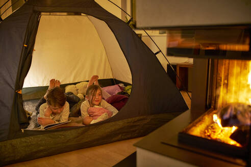 Brother and sister camping in the living room near fire place - DIKF00458