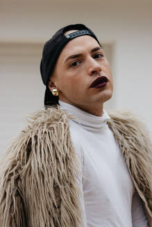 Nahaufnahme Porträt eines Transgender-Mannes, der eine Mütze mit Kunstpelz trägt - EYF04668