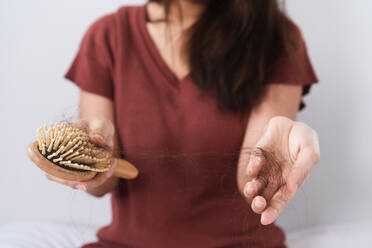 Close-Up Of Woman Holding Comb And Hair At Home - EYF04725