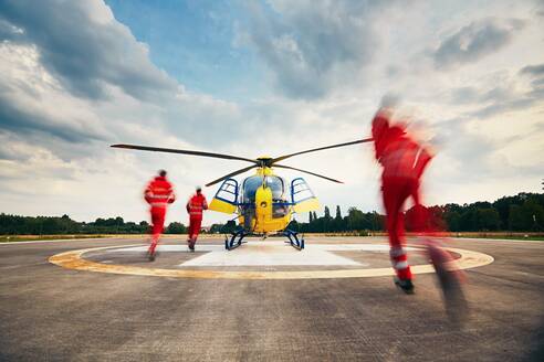 Rear View Of Paramedics Running Towards Helicopter - EYF04746