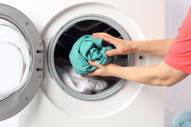 Cropped Hände des Mannes Putting Kleidung in der Waschmaschine zu Hause - EYF04803
