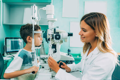 Seitenansicht des weiblichen Augenarztes Überprüfung der Sehkraft des Jungen im Krankenhaus - EYF04822