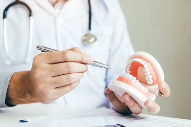 Midsection Of Dentist Holding Dentures In Hospital - EYF04823