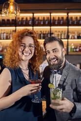 Portrait of happy couple socializing in a bar - ZEDF03262