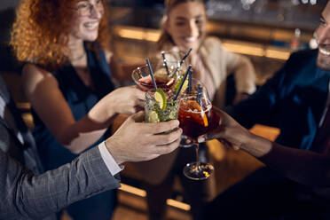 Glückliche Freunde, die in einer Bar zusammensitzen und auf ihre Cocktailgläser anstoßen - ZEDF03268