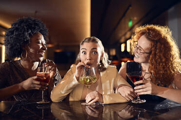 Glückliche Freunde, die sich in einer Bar bei Cocktails unterhalten - ZEDF03269