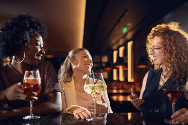 Glückliche Freunde, die sich in einer Bar bei Cocktails unterhalten - ZEDF03270