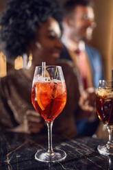 Cocktail glass on counter in a bar with happy people in background - ZEDF03275