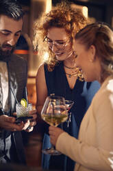 Freunde mit Cocktails und Smartphone, die sich in einer Bar treffen - ZEDF03284