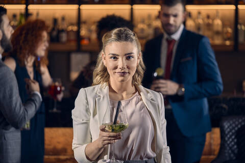 Porträt einer jungen Frau, die einen Cocktail in einer Bar trinkt, lizenzfreies Stockfoto