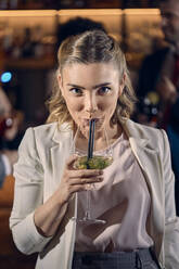 Portrait of a young woman having a cocktail in a bar - ZEDF03293