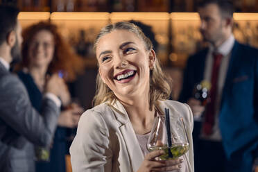 Porträt einer glücklichen jungen Frau, die einen Cocktail in einer Bar trinkt - ZEDF03295