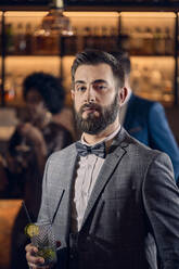 Portrait of a young man having a cocktail in a bar - ZEDF03297