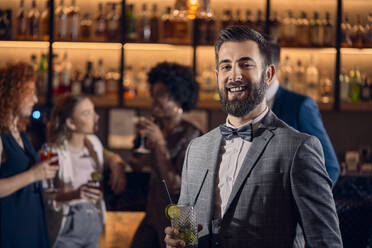 Porträt eines glücklichen jungen Mannes, der in einer Bar einen Cocktail trinkt - ZEDF03298