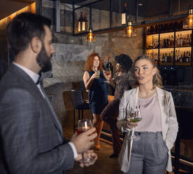 Mann und Frau mit Cocktails im Gespräch in einer Bar - ZEDF03311