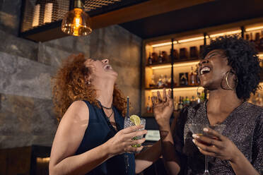 Zwei fröhliche Frauen unterhalten sich in einer Bar - ZEDF03312