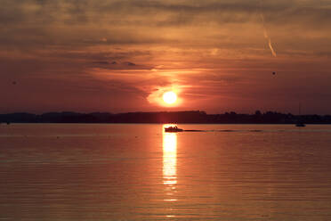 Deutschland, Bayern, Chiemsee, Silhouette eines einsamen Motorbootes bei stimmungsvollem Sonnenuntergang - ZCF00941