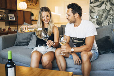 Couple sitting on the couch with glasses of white wine - MPPF00795