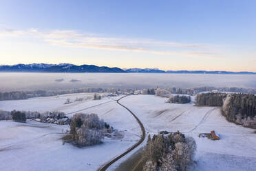 Germany, Bavaria, Hechenberg, Drone view of snow-covered countryside village at foggy dawn - SIEF09754