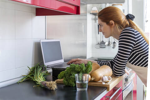 Young woman cooking healthy meal, using inline recipes stock photo
