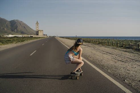 Back view of young woman skateboarding on asphalt road, Almeria, Spain - MPPF00813