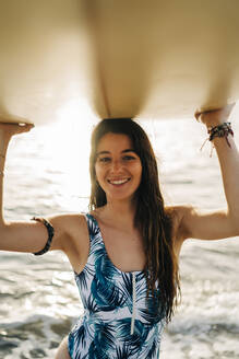 Portrait of happy young woman with surfboard on the beach, Almeria, Spain - MPPF00823