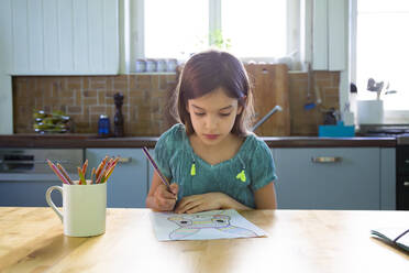 Kleines Mädchen sitzt am Küchentisch und zeichnet einen Osterhasen - LVF08813
