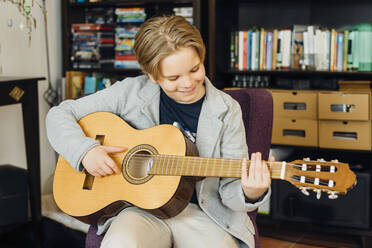 Boy playing guitar at home - MJF02442