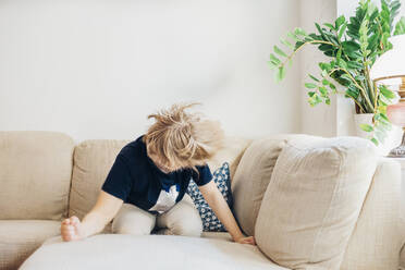 Junge, der zu Hause auf der Couch im Wohnzimmer herumtollt - MJF02462