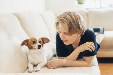 Junge mit Hund auf der Couch im Wohnzimmer zu Hause liegend - MJF02466
