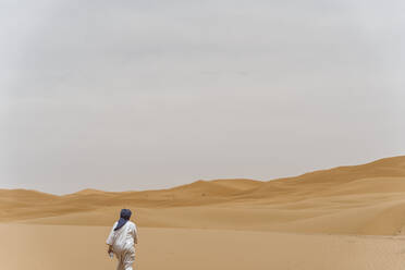 Man walking in the desert of Merzouga, Morocco - DAMF00346