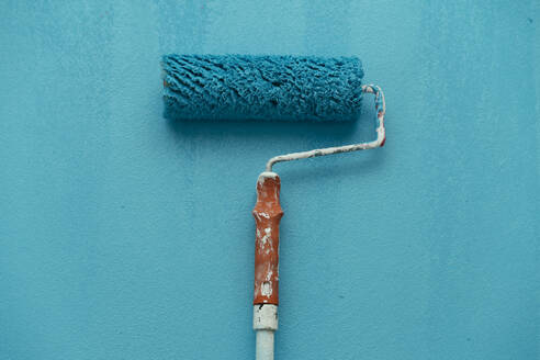 Studio shot of blue paint roller against blue background - PPXF00301