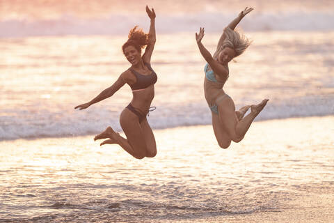 Two carefree women jumping on the beach, Costa Rica stock photo