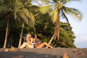 Zwei Frauen lesen ein Buch am Strand, Costa Rica - AMUF00076