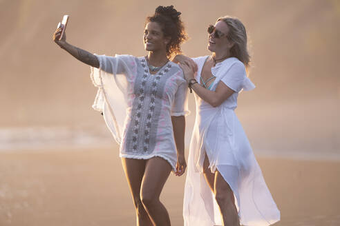 Zwei glückliche Frauen machen ein Selfie am Strand, Costa Rica - AMUF00080