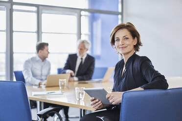 Portrait of businesswoman with tablet during a meeting in office - RORF02109
