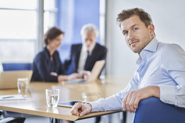 Porträt eines zuversichtlichen Geschäftsmannes während einer Sitzung im Büro - RORF02115