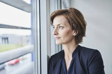 Porträt einer selbstbewussten Geschäftsfrau, die aus dem Fenster schaut - RORF02117