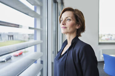 Portrait of confident businesswoman looking out of window - RORF02118