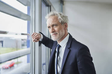 Portrait of confident businessman looking out of window - RORF02126