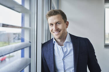 Portrait of smiling businessman at the window - RORF02134