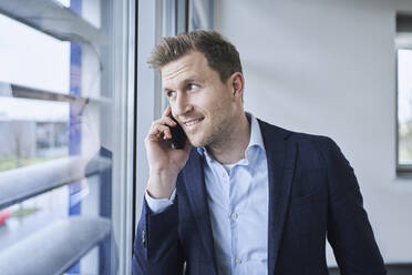 Geschäftsmann beim Telefonieren am Fenster - RORF02136