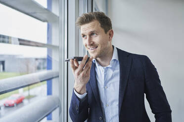 Businessman using cell phone at the window - RORF02138