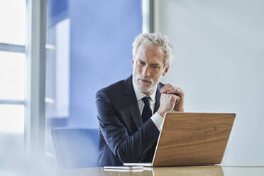 Focused businessman using laptop at desk in office - RORF02151