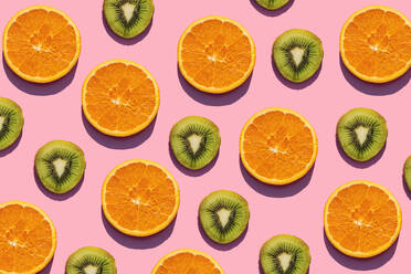 Muster aus Orangen- und Kiwi-Fruchtscheiben auf rosa Hintergrund - GEMF03573