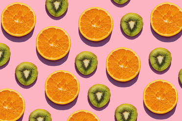 Pattern of orange and kiwi fruit slices against pink background - GEMF03573