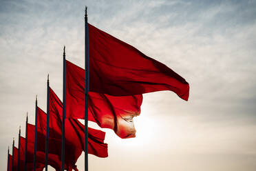 Low Angle View Of Red Flags Waving In Row Against Sky During Sunset - EYF04897