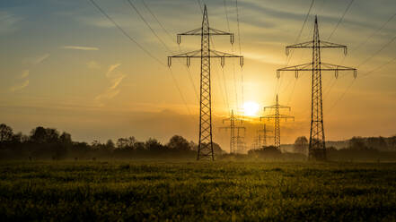 Strommasten auf dem Feld gegen den Himmel bei Sonnenuntergang - EYF04953